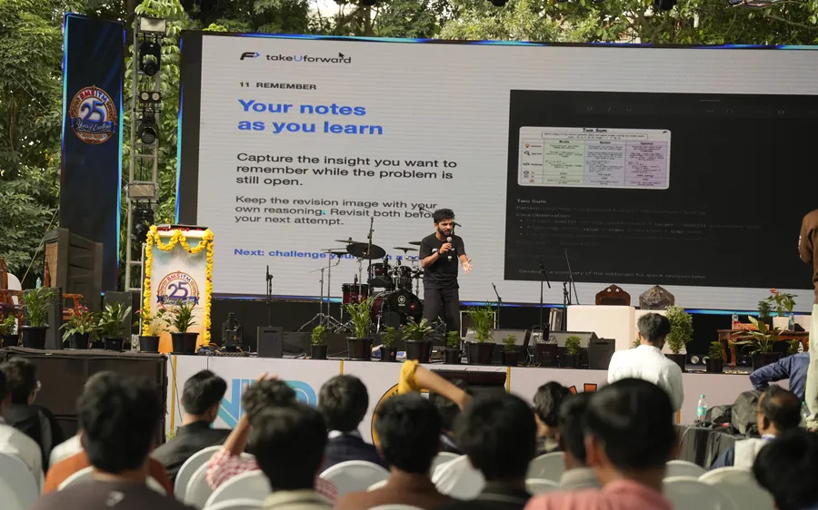Striver giving his talk on stage, with his slides on the big screen behind him